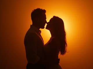 Couple in passionate embrace, silhouette against warm backlight, studio setting