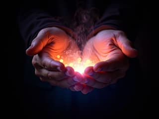 Hands emanating colorful energy, black background, studio photography