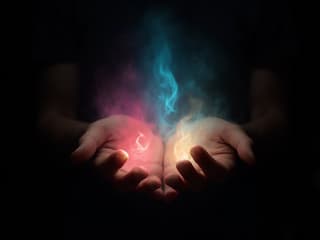 Hands emanating different colored auras, black background, studio photography