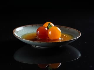 Molecular gastronomy dish with sauce spheres, black background, dramatic lighting