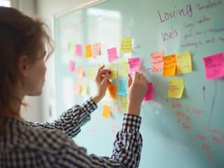 Person brainstorming with colorful sticky notes on a large whiteboard, creative environment