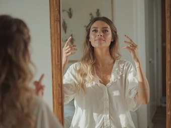 Person practicing positive body language in front of a mirror