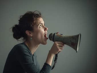 Studio portrait of a person silencing an imaginary critic, symbolizing overcoming self-doubt