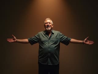 Studio shot of a caring man with open arms, ready to embrace, warm lighting