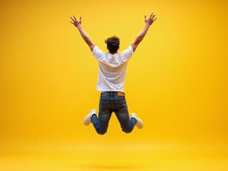 Vibrant studio shot of a person jumping with arms raised, energetic pose, bright background